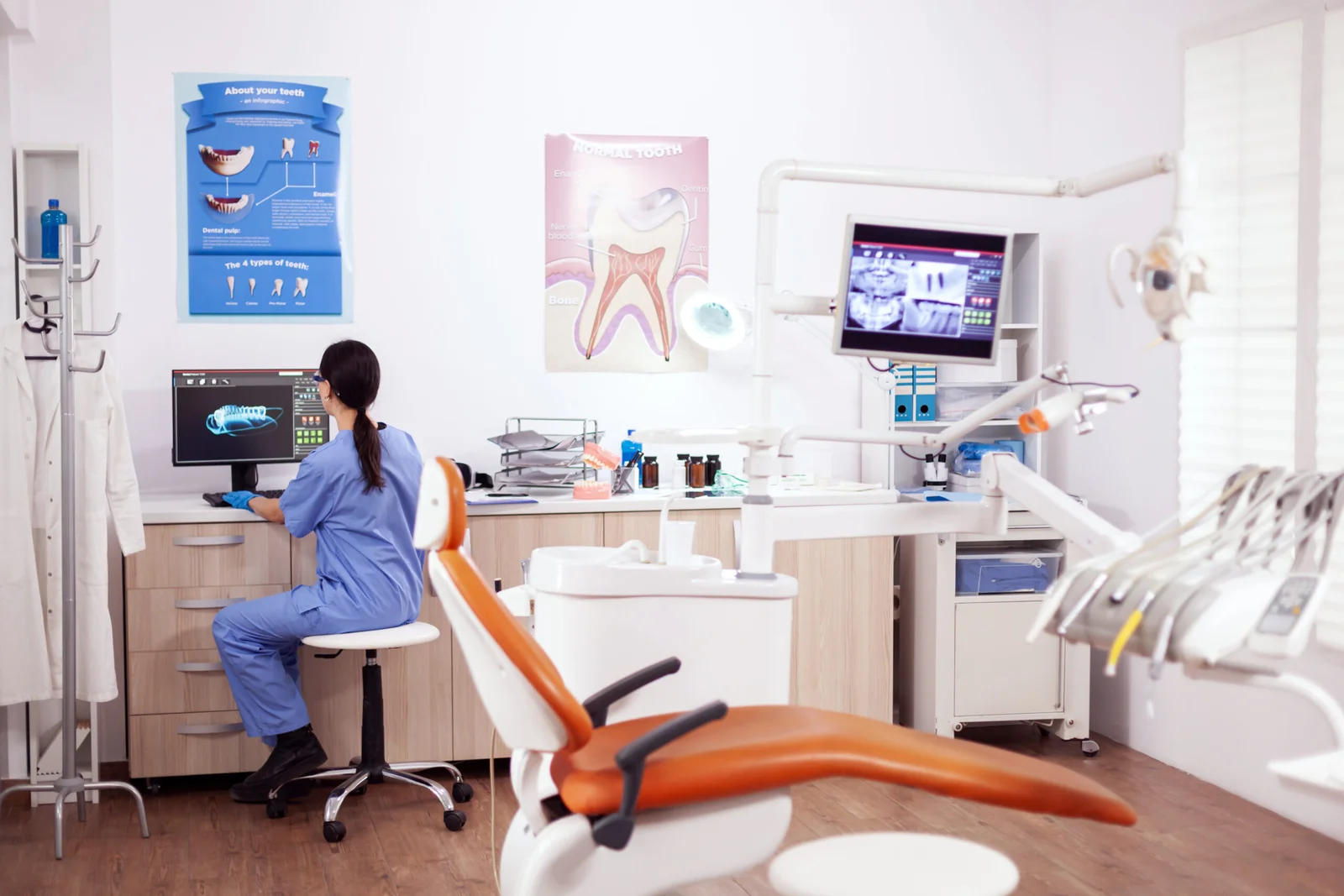stomatology-office-with-modern-equipment-nurse-wearing-blue-uniform-working-computer-scaled